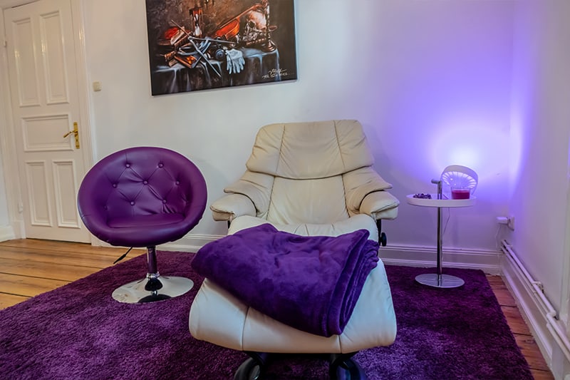 Therapiezimmer für Hypnose Hamburg mit weißem Ledersessel, lila Teppich und violettem  Barsessel